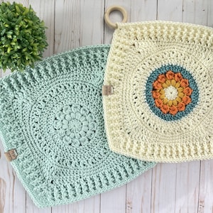 Peut inclure: Deux maniques en crochet avec un motif circulaire au centre. L'une est vert clair et l'autre est crème avec un centre multicolore.