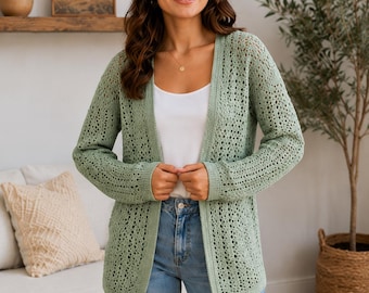 May include: A sage green open-front cardigan featuring a delicate, repeating crochet lace pattern throughout the body and sleeves, with solid ribbed trim along the front edges, neckline, and cuffs, worn over a simple white tank top and blue jeans.