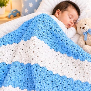 Peut inclure: Une couverture pour bébé crochetée à la main avec des rayures horizontales alternées de fil bleu clair et blanc. La couverture présente un motif texturé à points ouverts et est posée sur un nourrisson endormi à côté d'un ours en peluche.