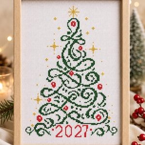 May include: A framed cross-stitch embroidery on white fabric featuring a stylised green Christmas tree with swirling branches, red circular ornaments, and small yellow stars. The year 2027 is stitched in red at the bottom of the tree design.