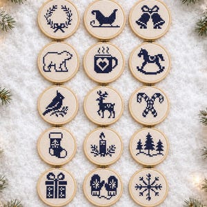 May include: Fifteen circular wooden embroidery hoops containing navy blue cross-stitch designs on white fabric. The patterns include a wreath, sleigh, bells, polar bear, mug, rocking horse, bird, deer, candy canes, stocking, candle, trees, gift, mittens, and snowflake.