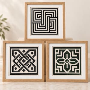 May include: Three square framed cross-stitch artworks featuring geometric patterns. The top piece displays a black and white maze design. The bottom left piece shows a black and white interlaced knot pattern. The bottom right piece features a dark green and white floral-inspired geometric motif.