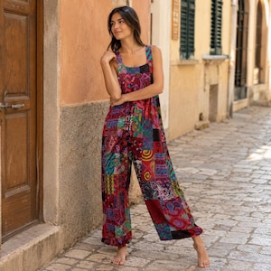 Puede incluir: Un mono sin mangas con un vibrante estampado de patchwork en tonos rojos, morados, azules y verdes. La prenda presenta un escote cuadrado, perneras anchas y un corte holgado, confeccionado con múltiples paneles de tela con diseños variados.