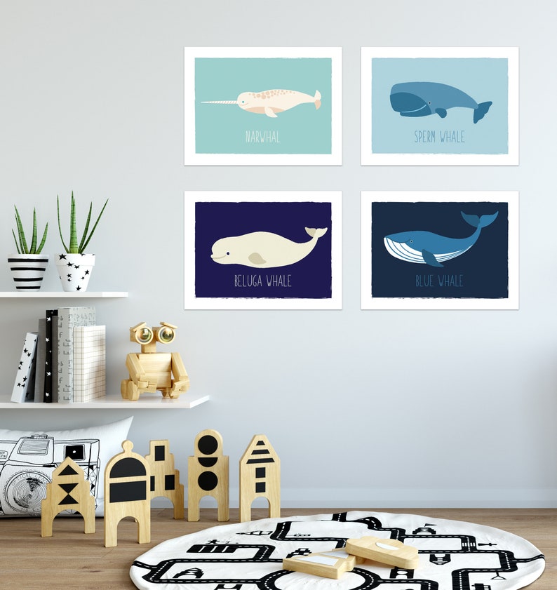 May include: Four framed art prints featuring cartoon whales: a narwhal, sperm whale, beluga whale, and blue whale. Each print has a different background color and the whale's name is printed below the image.
