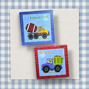 May include: Two square wall art pieces featuring construction vehicles. The top piece has a blue border and shows a yellow cement truck with a brown mixer and the text CEMENT TRUCK. The bottom piece has a red border and shows a purple dump truck with a green bed and the text DUMP TRUCK.