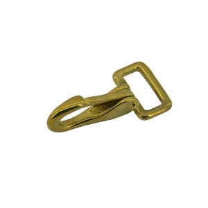 May include: A gold-toned metal swivel snap hook featuring a spring-loaded gate and a rectangular loop attachment point. The hardware has a smooth, polished finish and a curved hook design, commonly used for connecting straps or leashes.