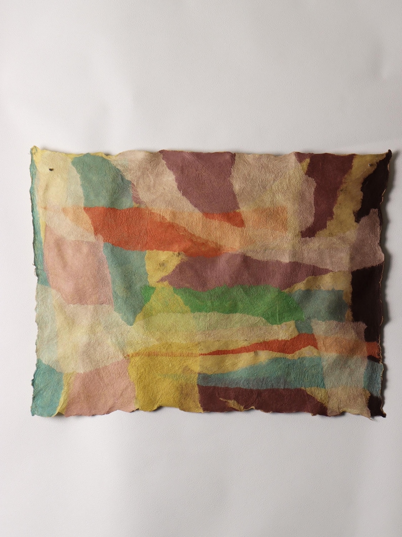 May include: A rectangular piece of textured, handmade paper featuring an abstract collage of overlapping, irregular shapes in muted tones of sage green, dusty pink, burnt orange, mustard yellow, deep maroon, and cream with deckled edges.