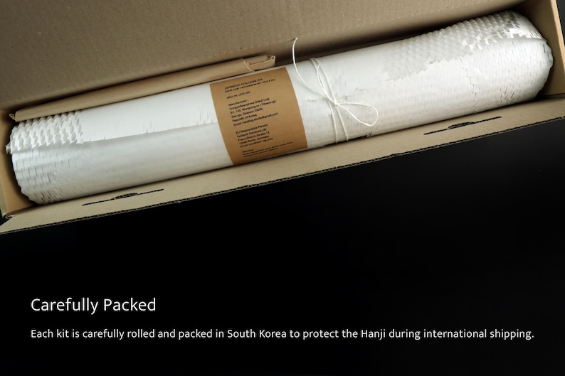 May include: A white, textured roll of Hanji paper secured with white string, wrapped in a brown paper label with printed text, and placed inside a rectangular cardboard shipping box for protection during transit.