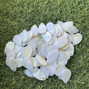 May include: A collection of numerous white, teardrop-shaped mother-of-pearl charms. Each individual piece features a smooth, iridescent surface with a small, pre-drilled hole at the top, designed for use as a component in jewelry making projects.