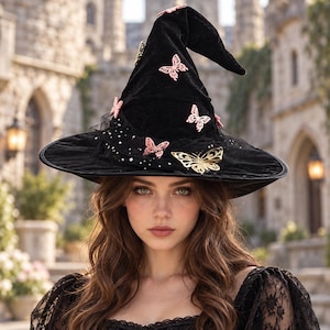 May include: A black velvet pointed hat featuring a wide brim and a tall, slightly curved crown. The hat is decorated with several small pink butterfly cutouts and one larger gold butterfly cutout, along with a layer of black tulle with white dots.