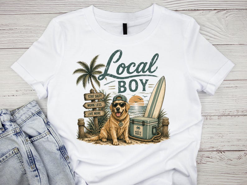 May include: A white t-shirt featuring a graphic of a golden retriever wearing a baseball cap and sunglasses. The design includes a palm tree, a surfboard, a cooler, and a wooden sign with the text Local Boy, Stay Salty, Work Less, Live More.