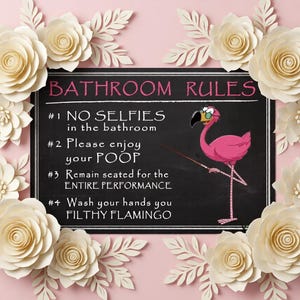 May include: A rectangular black sign with white text reading BATHROOM RULES, #1 NO SELFIES in the bathroom, #2 Please enjoy your POOP, #3 Remain seated for the ENTIRE PERFORMANCE, #4 Wash your hands you FILTHY FLAMINGO, featuring a pink flamingo illustration.