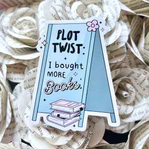May include: A blue and white sticker with a book stack and the text "PLOT TWIST: I bought MORE Books".