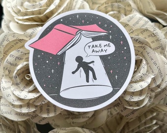 May include: A black and white sticker with a pink book flying over a person. The book is open and the text "TAKE ME AWAY" is in a speech bubble above the person. The background is a black starry sky.