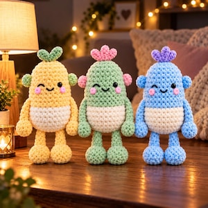 Può includere: Tre peluche realizzati a mano all'uncinetto in fila. Il giocattolo a sinistra è giallo, quello centrale è verde chiaro e quello a destra è azzurro. Ognuno presenta una pancia bianca, piccole braccia rotonde, due gambe e un piccolo ciuffo.
