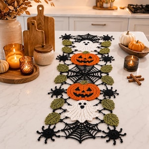 May include: A rectangular crochet table runner featuring a black spiderweb pattern interspersed with white ghosts, orange jack-o'-lantern pumpkins, and green leaves. The design includes small black spider motifs along the edges of the runner.