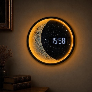 May include: A circular wall clock featuring a textured, illuminated crescent moon surface on the left and a dark, starry night sky background on the right. A digital display in the centre shows the time as 15:58 in bright white numerals.