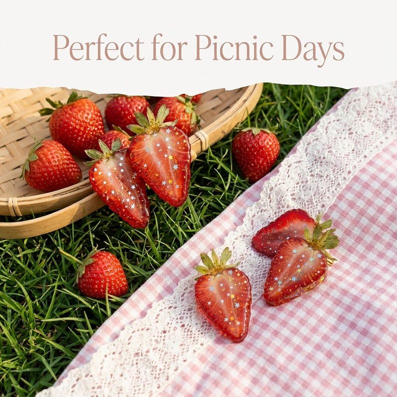May include: A collection of fresh red strawberries, some whole and some sliced, featuring small star-shaped glitter accents on the cut surfaces. The fruit is arranged in a woven bamboo basket and on a pink and white gingham cloth with lace trim.