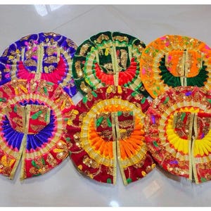 May include: Six circular, pleated garments featuring vibrant, multi-coloured fabric panels in shades of purple, pink, green, orange, red, and yellow. Each piece is heavily embellished with gold-toned metallic embroidery, sequins, and decorative trim.