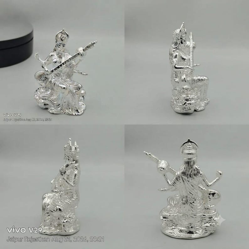 May include: A shiny silver-toned figurine depicting a seated deity playing a stringed instrument. The figure features intricate detailing on the clothing and jewelry, with four arms, a crown, and a base. The sculpture is shown from four angles.