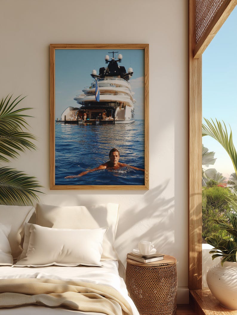 May include: A framed wall art print featuring a large white multi-deck yacht anchored in deep blue ocean water, with a person swimming in the foreground. The yacht has multiple levels, a dark upper structure, and a blue flag flying from the stern.