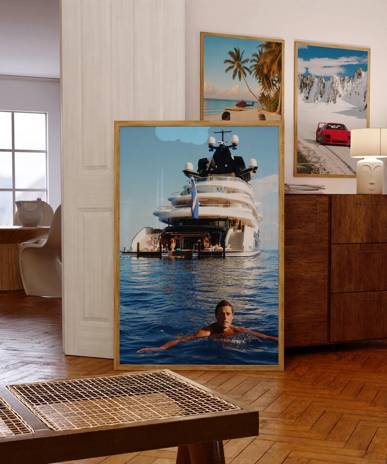 May include: A framed vertical wall art print featuring a large white luxury yacht floating on deep blue ocean water, with a person swimming in the foreground. The yacht has multiple decks and a blue flag, set against a clear sky with a small cloud.