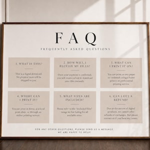 May include: A rectangular sign with a white background and a thin brown frame. The text FAQ FREQUENTLY ASKED QUESTIONS appears at the top. Below are six beige boxes containing numbered questions and answers regarding digital download policies.