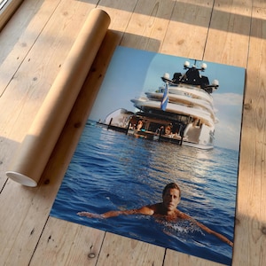 May include: A rectangular photographic print featuring a large white multi-deck yacht anchored in deep blue water with a person swimming in the foreground. The print is displayed next to a cylindrical brown cardboard shipping tube.