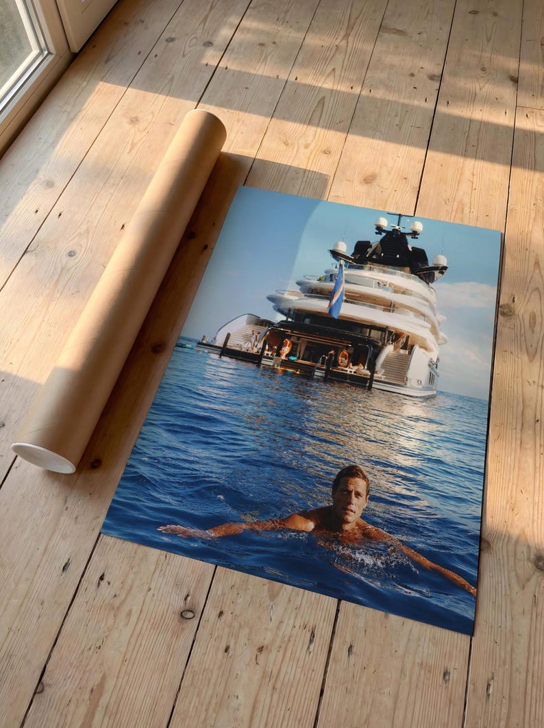 May include: A rectangular photographic print featuring a large white multi-deck yacht anchored in deep blue water with a person swimming in the foreground. The print is displayed next to a cylindrical brown cardboard shipping tube.