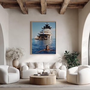 May include: A framed wall art print featuring a large white luxury yacht anchored in deep blue ocean waters with a person swimming in the foreground. The image captures the vessel's multi-level deck structure and the clear, calm sea surface.