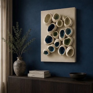 May include: A rectangular wall art piece featuring a beige textured base adorned with numerous organic, bowl-shaped ceramic protrusions. These individual elements have rough, off-white exteriors and smooth, deep blue or light green interiors.