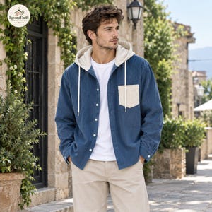 May include: A blue corduroy button-down shirt featuring a contrasting cream-colored hood with white drawstrings and a single chest pocket. The shirt is worn over a plain white t-shirt and paired with light beige trousers in a casual style.