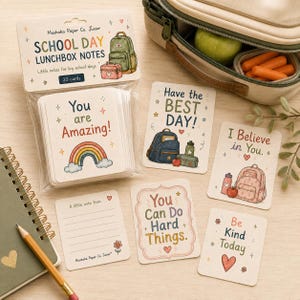 May include: A set of 30 Muskoka Paper Co. Junior School Day Lunchbox Notes in clear packaging, featuring colourful illustrations of backpacks, rainbows, and hearts. Individual cards display encouraging phrases like You are Amazing, Have the BEST DAY, I Believe in You, You Can Do Hard Things, and Be Kind Today.