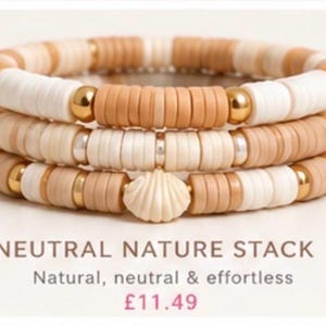 Op de afbeelding: Een stapel van drie armbanden gemaakt van platte, ronde kleikralen in tinten crème, beige en bruin. De armbanden zijn voorzien van metallic gouden bolvormige tussenstukken en een crèmekleurige schelpbedel. De tekst luidt NEUTRAL NATURE STACK.