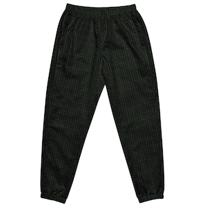 May include: Black joggers featuring a subtle, repeating dark green geometric dot pattern. These trousers include an elasticated waistband with a drawstring, side pockets, and elasticated cuffs at the ankles, providing a tapered fit throughout the legs.