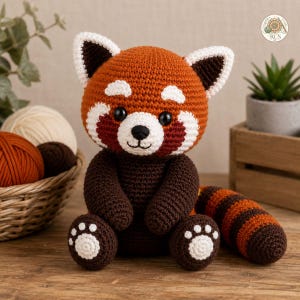 May include: A crocheted red panda stuffed animal with a rust-orange head, white facial markings, and dark brown limbs. It features black plastic eyes, a stitched nose and mouth, and a long, striped tail. The feet have white paw pad details.