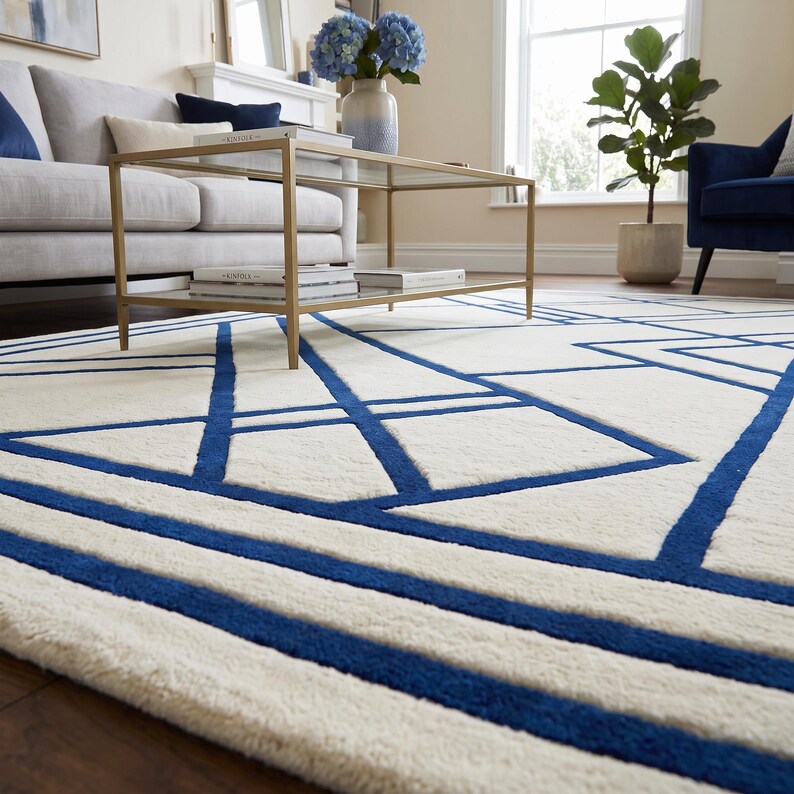 Pode incluir: Um tapete retangular com uma base de cor creme e um padr&atilde;o geom&eacute;trico arrojado de linhas azul-escuras que se cruzam. O design consiste em v&aacute;rias formas angulares e riscas paralelas que criam um efeito visual linear e estruturado.