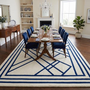 Pode incluir: Um tapete retangular com uma base de cor creme e um padr&atilde;o geom&eacute;trico arrojado de linhas grossas azul-marinho. O design consiste em linhas retas que se cruzam e bordas retangulares que emolduram o centro do tapete.