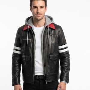 Könnte beinhalten: Eine schwarze Lederjacke mit grauem Kapuzeneinsatz, rotem Kragen und zwei weißen horizontalen Streifen an jedem Ärmel. Die Jacke verfügt über einen Frontreißverschluss, zwei Brusttaschen mit Reißverschluss und zwei untere Pattentaschen.