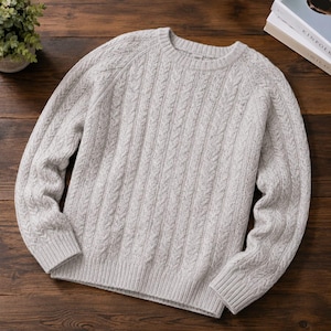 May include: A light gray crew neck sweater featuring a vertical cable knit pattern throughout the body and sleeves. The garment is constructed with long sleeves, ribbed cuffs, and a ribbed hem, showcasing a textured, speckled knit fabric design.