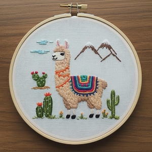 May include: A circular embroidery hoop containing white fabric with a hand-stitched design of a tan llama. The llama wears a colorful saddle blanket and orange neck trim. The scene includes green cacti with red flowers, brown mountains, and blue clouds.