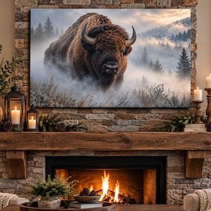 May include: A large rectangular wall art print featuring a brown bison standing in a misty, mountainous forest landscape. The artwork is displayed above a stone fireplace mantel with lit candles, greenery, and a burning fire below.