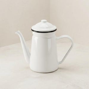 May include: A white enamel coffee pot with a tall, cylindrical body, a curved spout, and a matching lid. The rim of the lid and the top edge of the pot feature a thin, contrasting black trim. It includes a side handle for pouring.