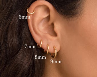 May include: Four gold hoop earrings worn in a single ear, labeled with their respective sizes: a 6mm hoop in the upper cartilage, and 7mm, 8mm, and 9mm hoops positioned along the earlobe. Each hoop is a simple, smooth, circular metal ring.