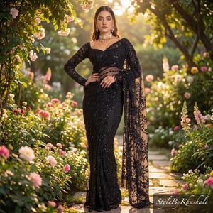 May include: A black saree featuring intricate lace embroidery and sequin embellishments, long sleeves, and a fitted bodice. The garment is draped elegantly with a sheer panel and a scalloped border, showcasing detailed floral patterns throughout the fabric.