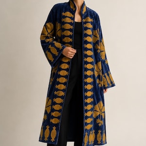 May include: A long, deep blue velvet coat featuring intricate gold-coloured embroidery. The design includes vertical rows of repeating oval-shaped motifs along the front opening and large, stylized floral patterns on the sleeves and lower panels.