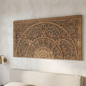 Puede incluir: Un panel de pared rectangular de madera con intrincados patrones florales y de mandala tallados a mano. La madera marrón natural muestra detallados arabescos simétricos, motivos de hojas y un diseño central de rayos de sol en un borde.