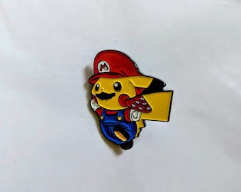 Könnte beinhalten: Ein Metall-Emaille-Pin, der eine gelbe Kreatur mit schwarzem Schnurrbart zeigt, die eine rote Mütze mit weißem M-Logo und eine blaue Latzhose trägt. Die Figur hält einen rot-weiß gepunkteten Pilz in einer Hand und hat einen gelben Schwanz.