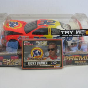 Może przedstawiać: Model samochodu wyścigowego Tide Racing #32 Ricky'ego Cravena w skali 1/24. Samoch&oacute;d znajduje się w przezroczystej plastikowej gablocie z obrotową podstawą tunelu aerodynamicznego. Pudełko zawiera r&oacute;wnież kartę ze zdjęciem Cravena i logo Tide.