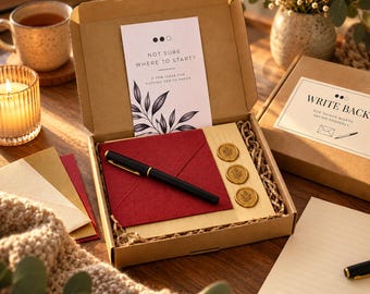 May include: A stationery kit in a cardboard box containing a black fountain pen, a deep red envelope, three gold wax seals with leaf imprints, and a card with the text NOT SURE WHERE TO START? A FEW IDEAS FOR PUTTING PEN TO PAPER.